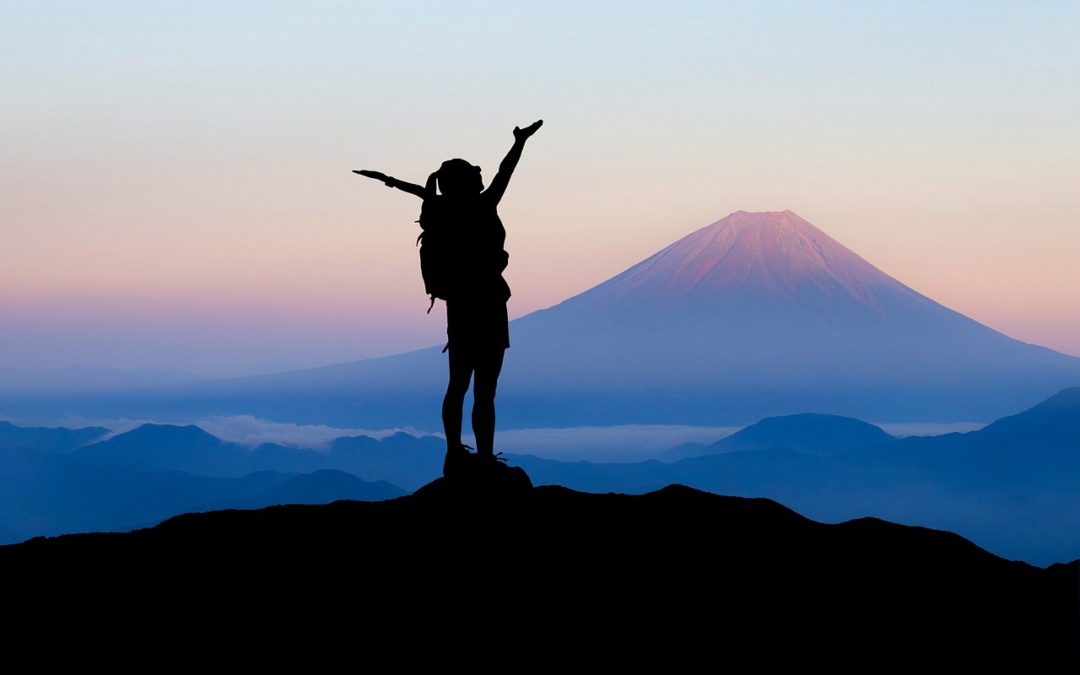 Woman on top of mountain with arms raised